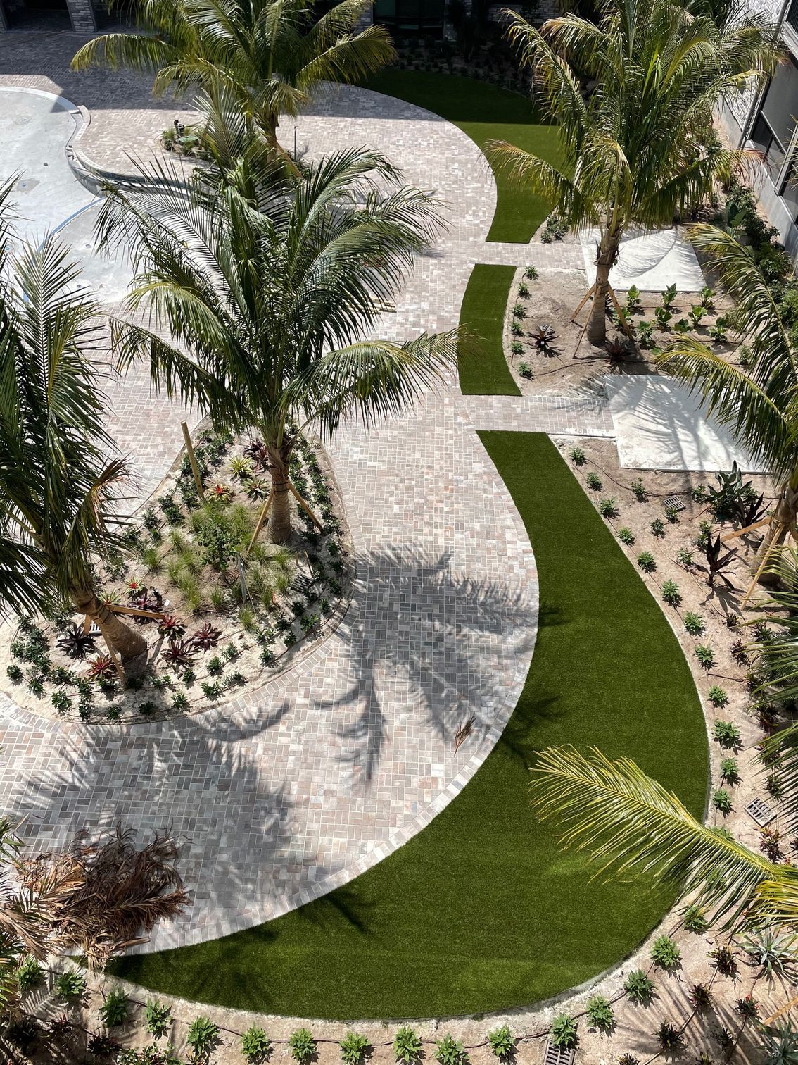 An aerial view of a lush green lawn surrounded by palm trees.