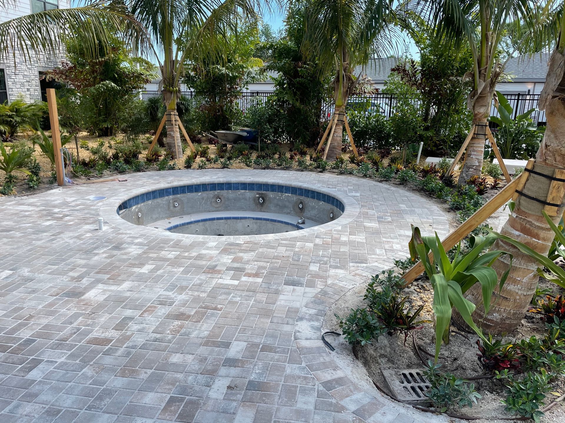 There is a hot tub in the middle of the patio surrounded by palm trees.