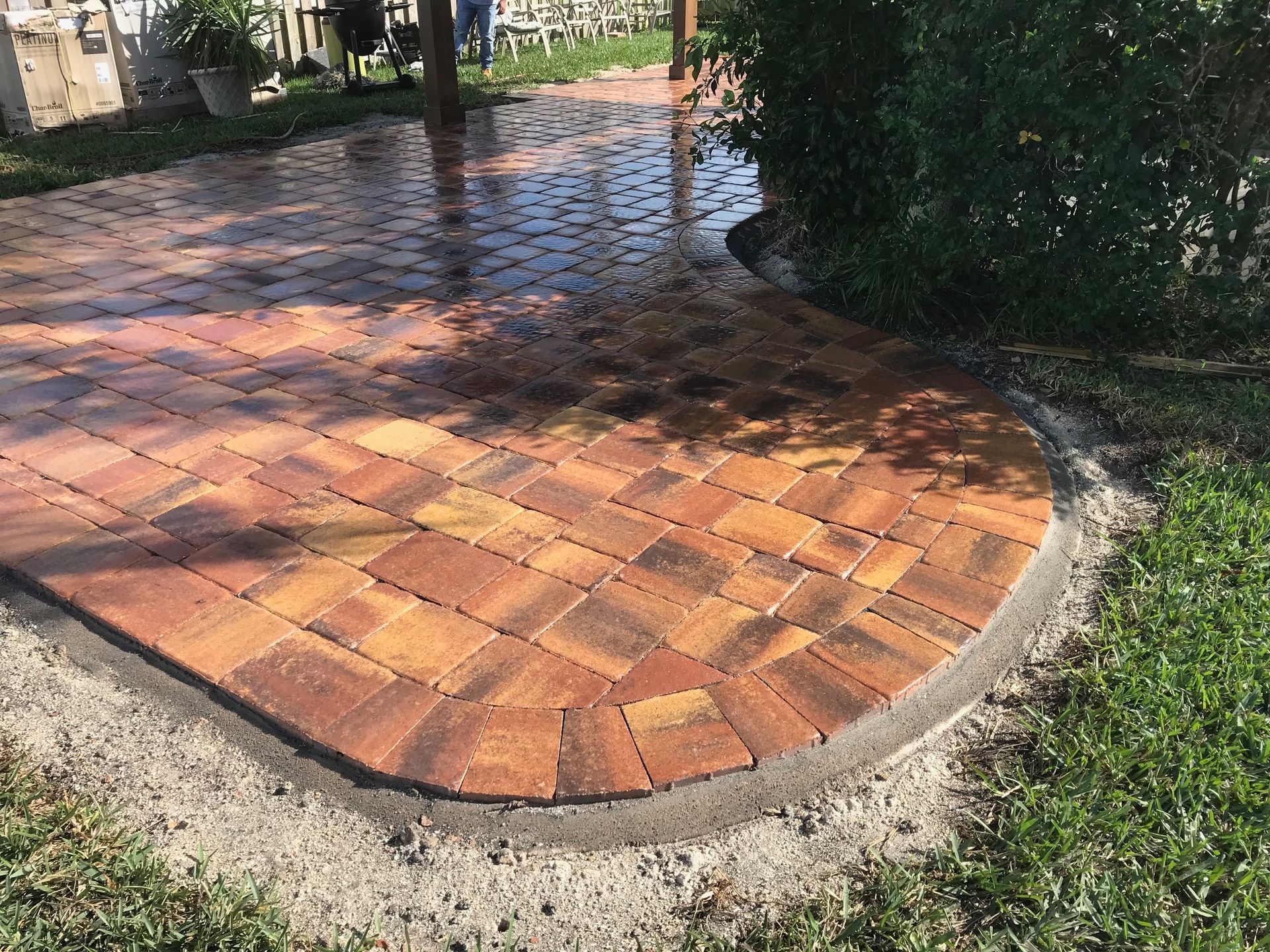 A brick walkway is being built in a backyard.