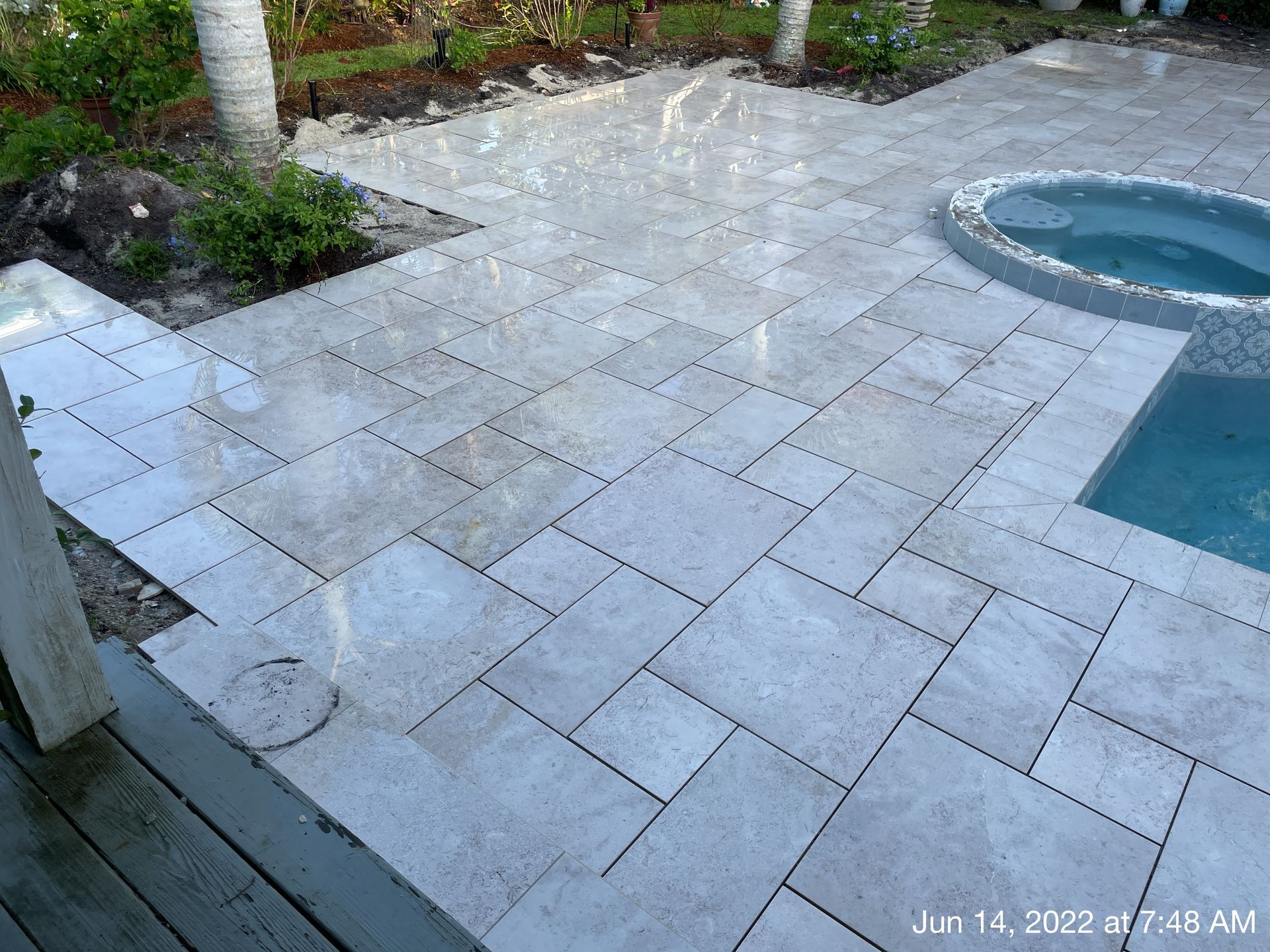 A patio with a pool and a hot tub in the background