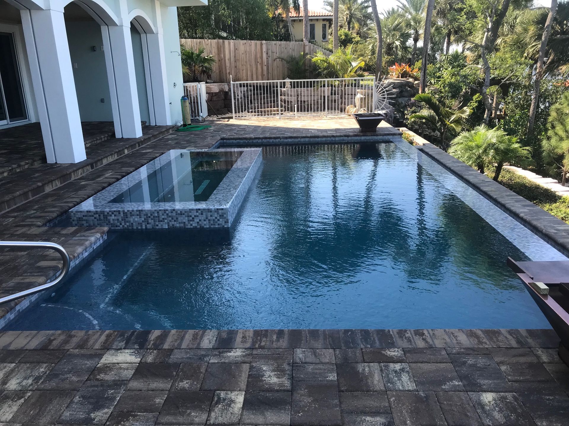 There is a large swimming pool in the backyard of a house.
