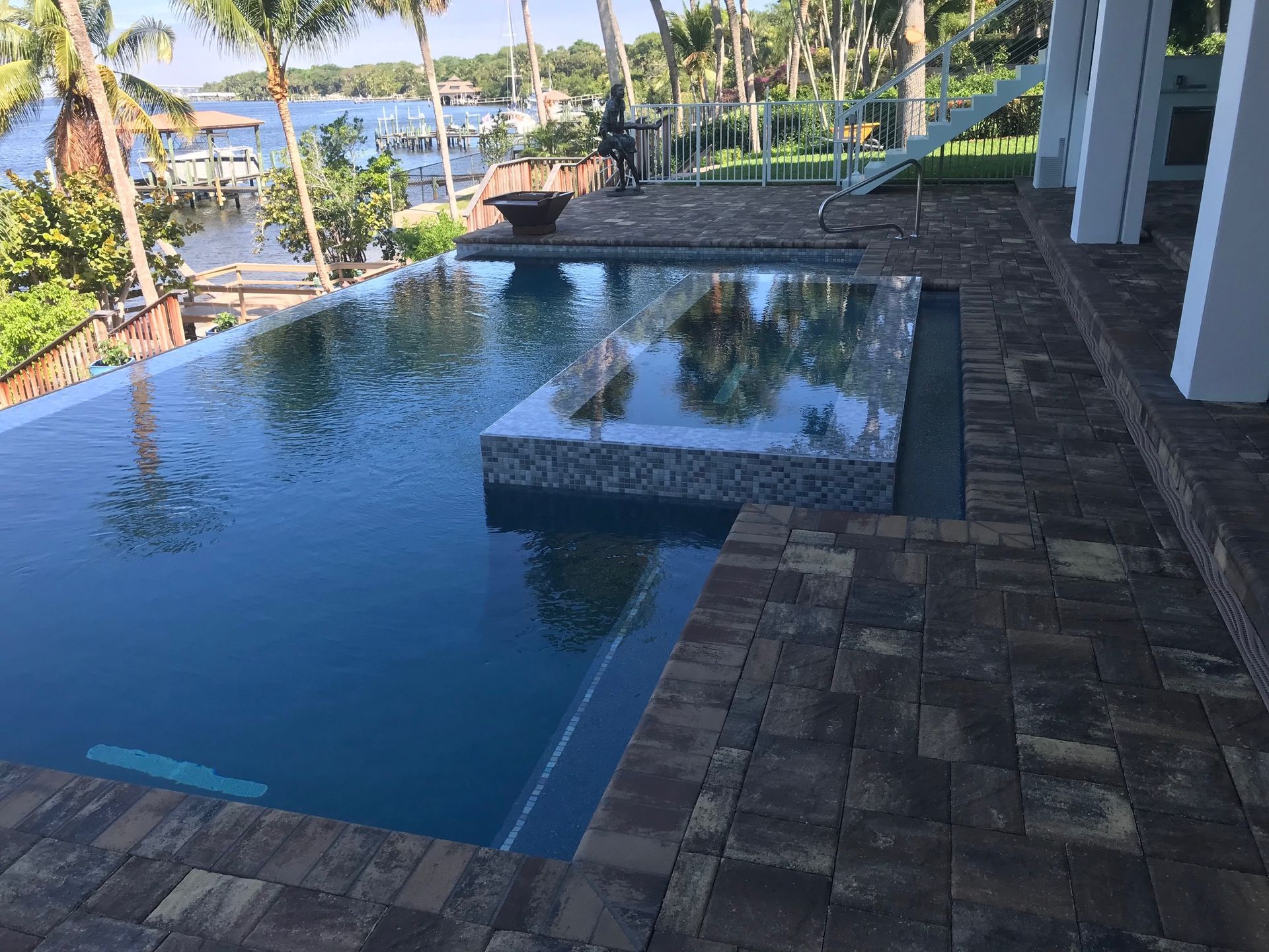 A large swimming pool with a view of the water and palm trees.