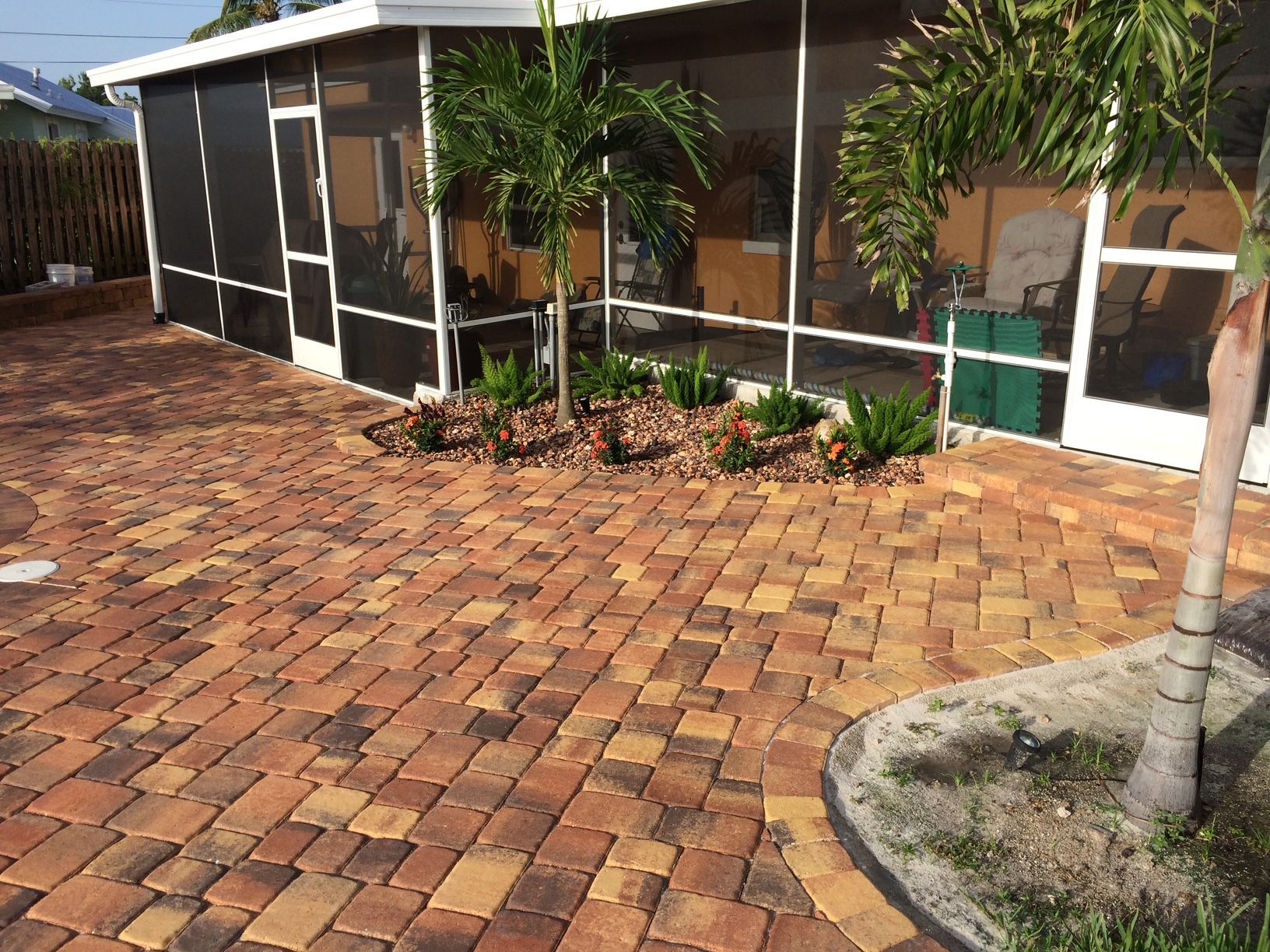 A house with a screened in porch and a brick driveway