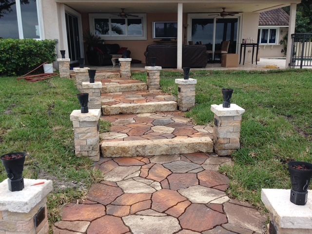 A stone walkway leading to a house with stairs