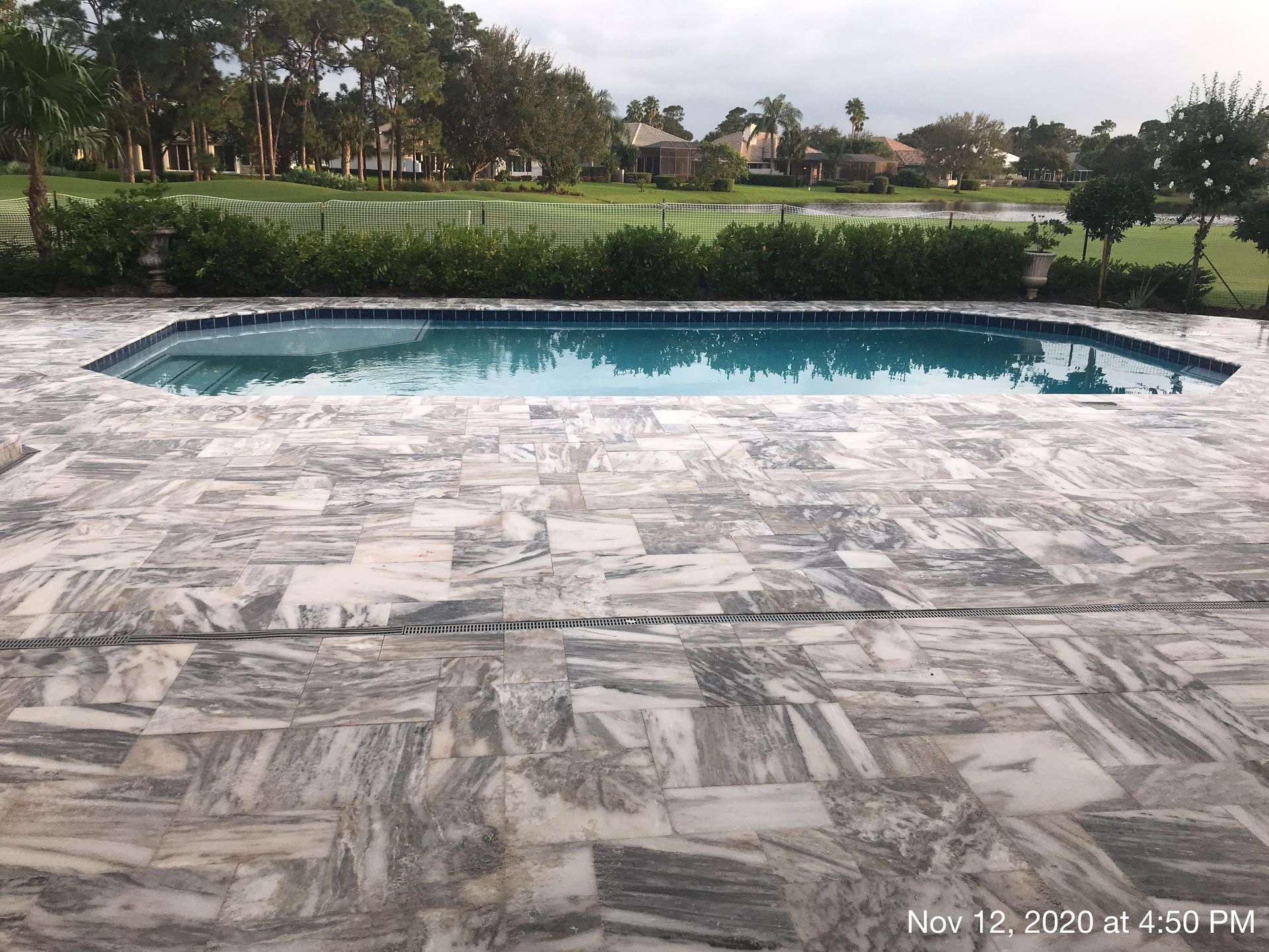 A large swimming pool with a patio in front of it