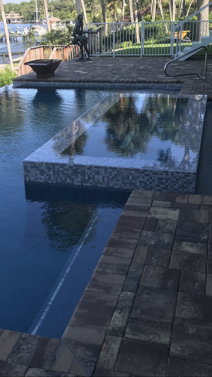 A large swimming pool surrounded by bricks and a patio.