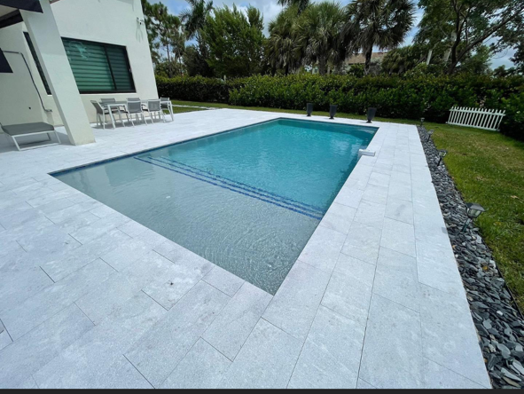 A large swimming pool is in the backyard of a house