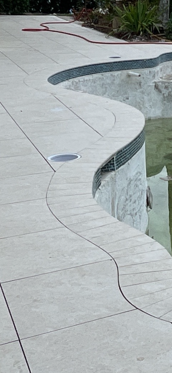 A concrete walkway leading to a swimming pool.