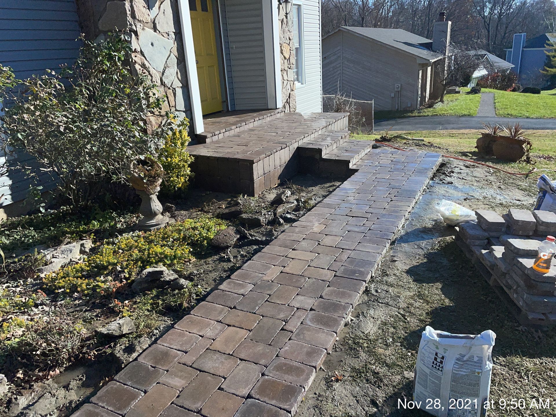 A brick walkway is being built in front of a house