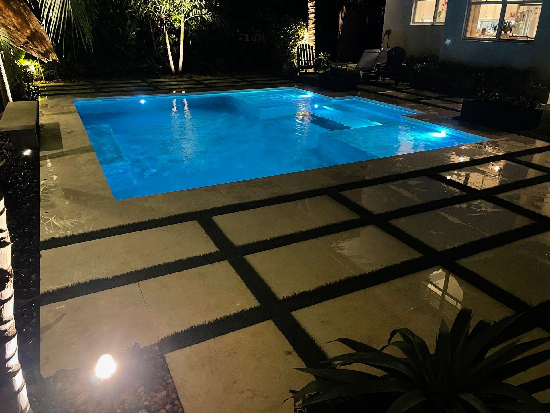 A large swimming pool is lit up at night.