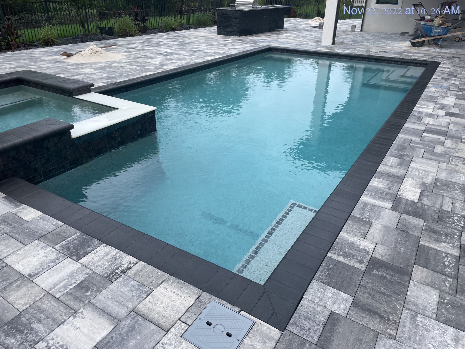 A large swimming pool is surrounded by a brick patio.