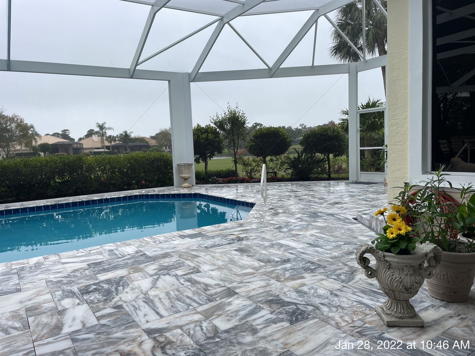 A large swimming pool is surrounded by a screened in area.