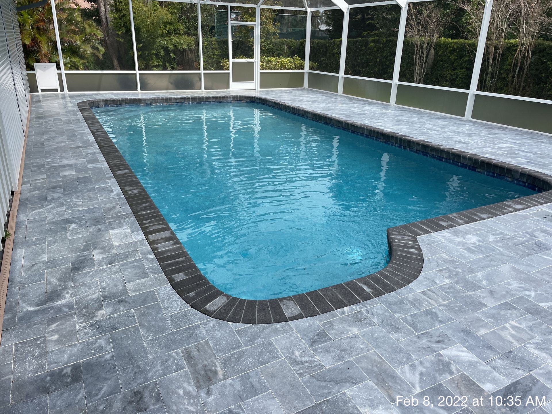 A large swimming pool with a screened in area around it