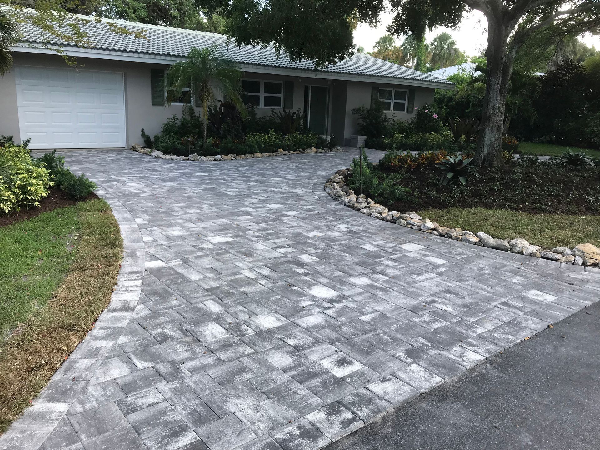 A brick driveway leading to a house with a garage.