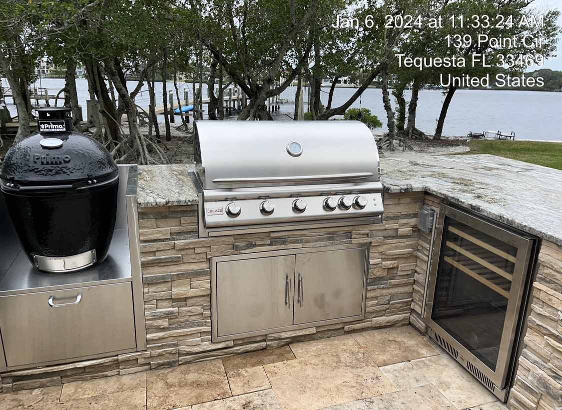 A stainless steel grill is sitting on top of a brick wall.
