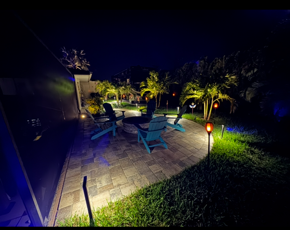A patio with chairs and a table at night.