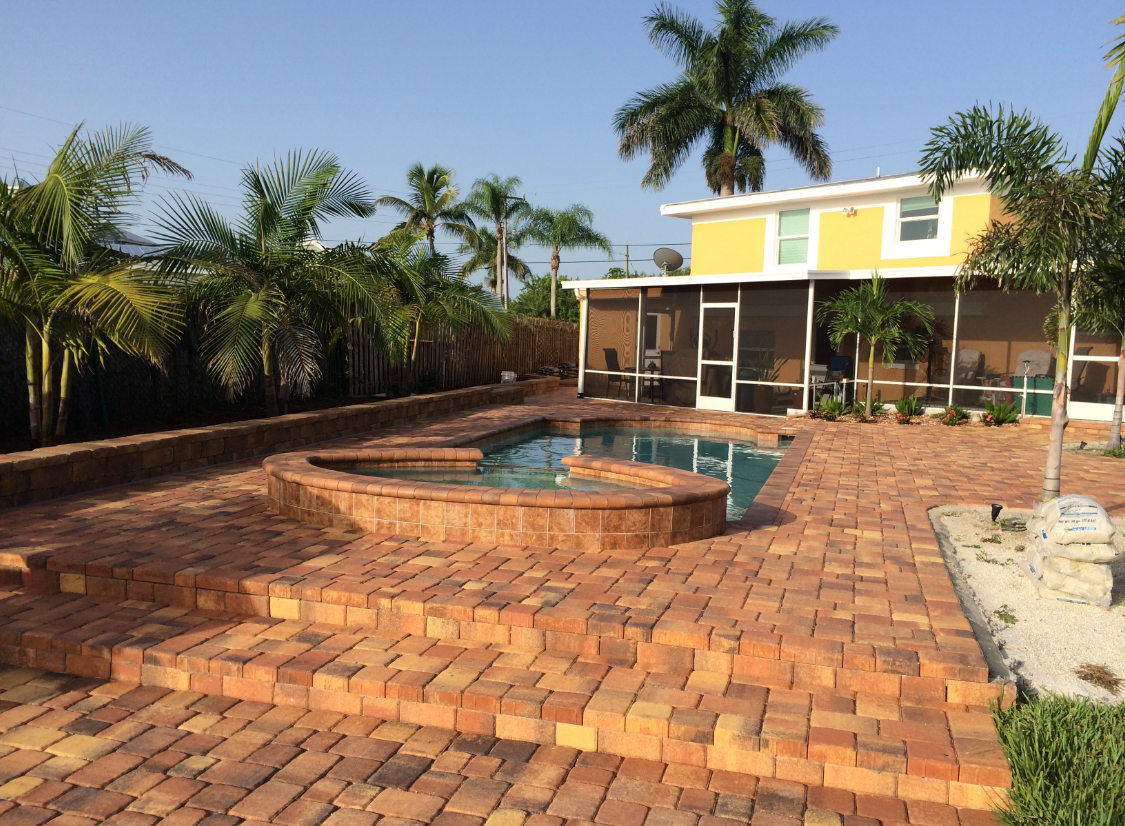A yellow house with a screened in porch and a swimming pool