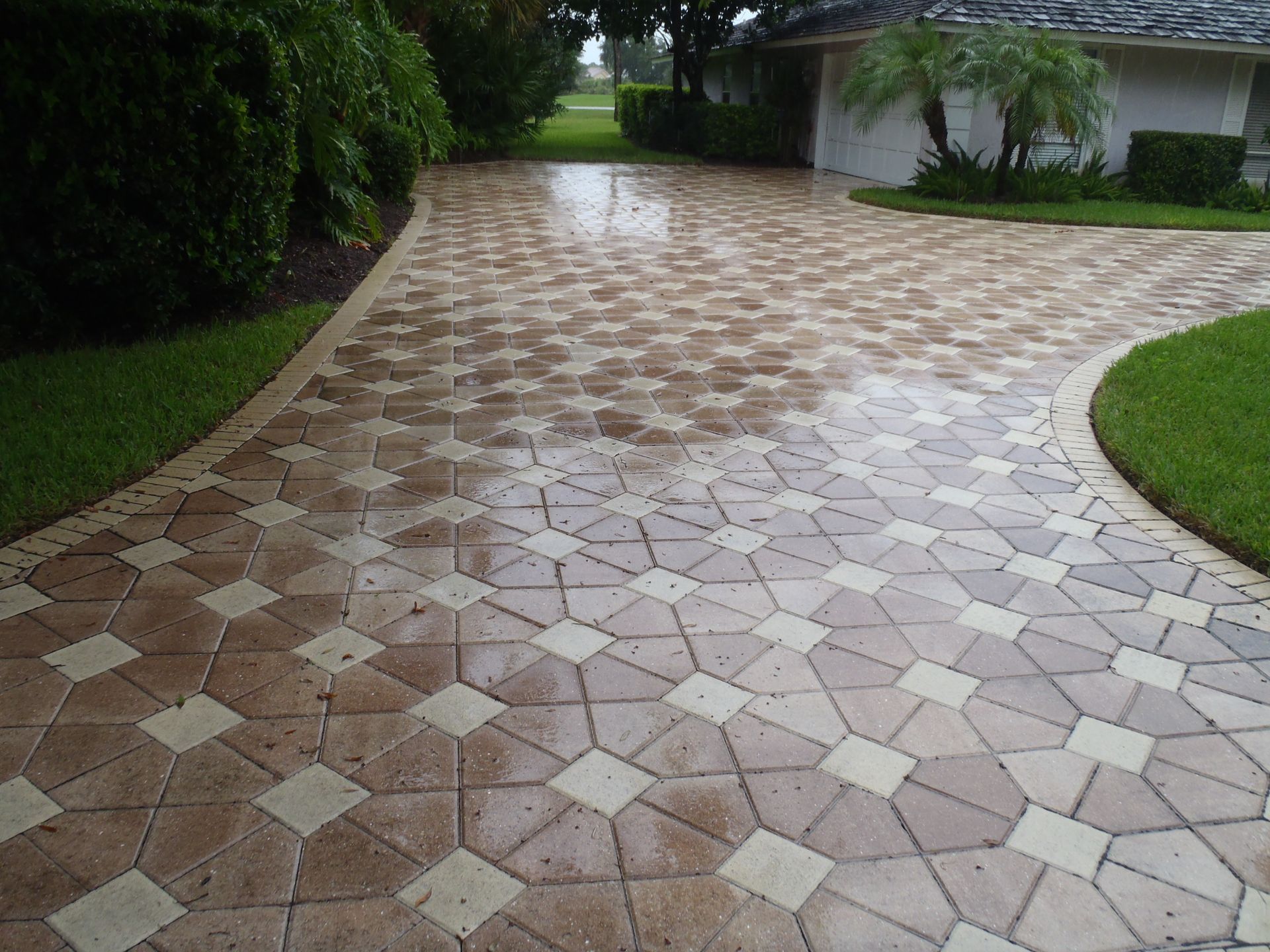 A brick driveway leading to a white house