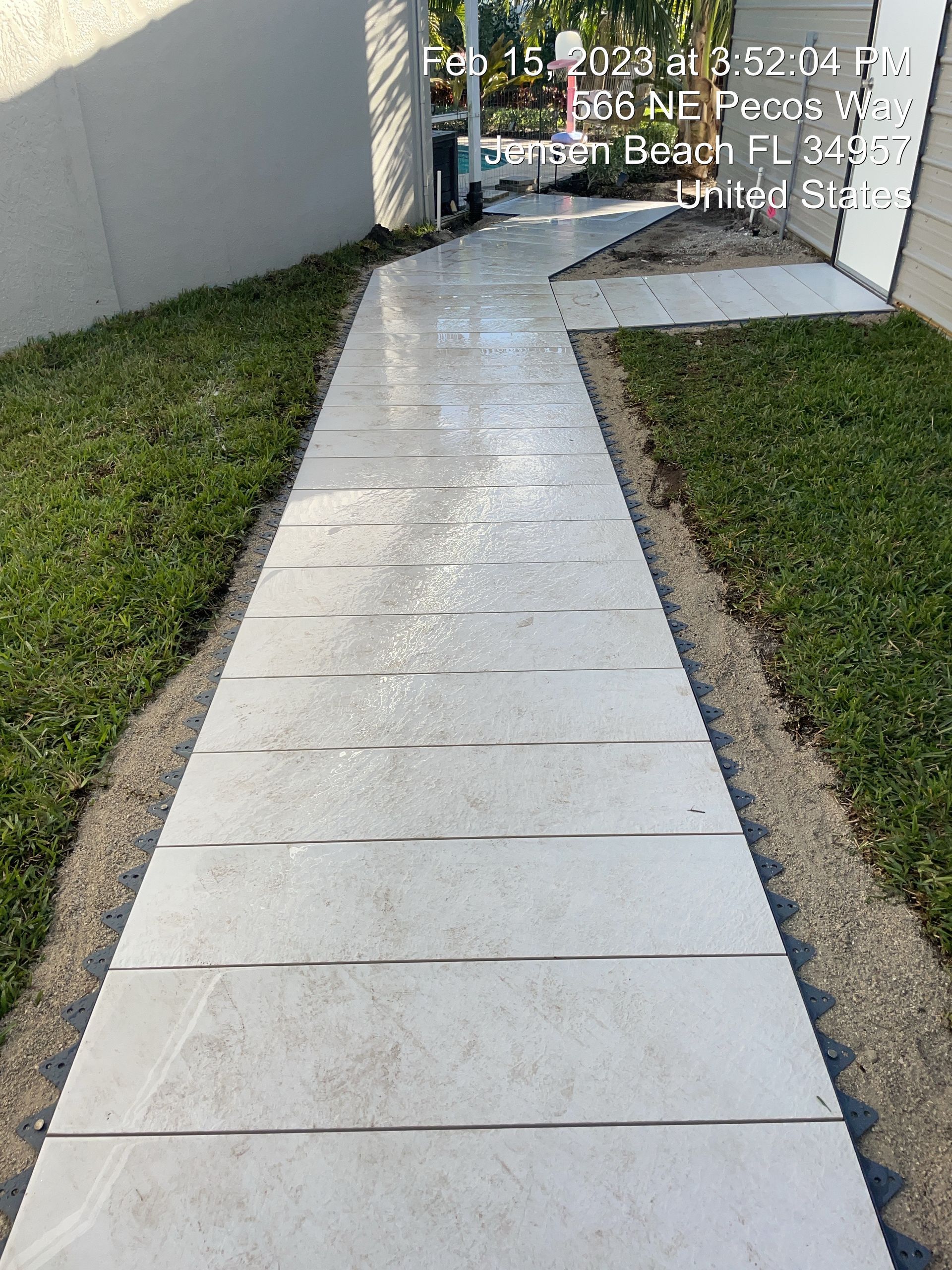A white tiled walkway leading to a house.