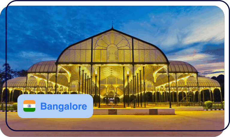 Illuminated glass conservatory at dusk with a “Bangalore” label in the foreground