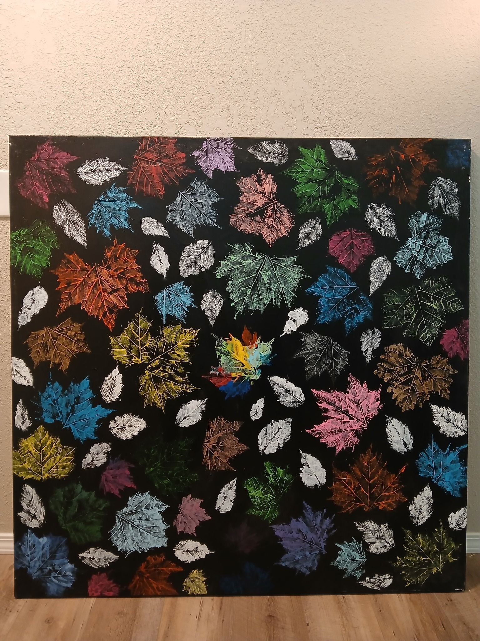 Colorful leaf mosaic on black background. Some white leaves scattered.