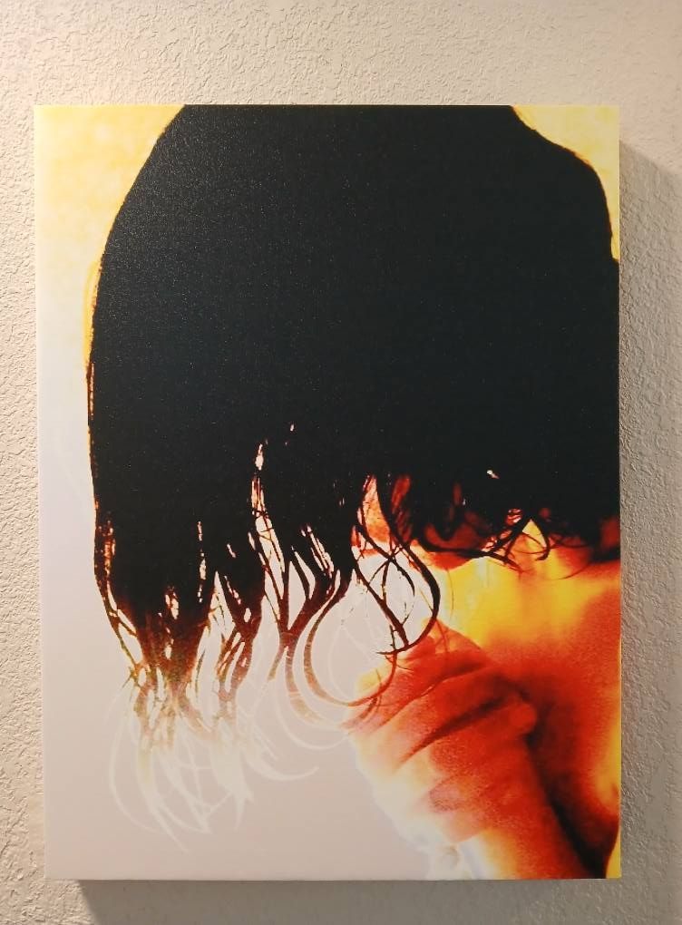 Black hair against a yellow and orange gradient, person’s arm and shoulder visible.