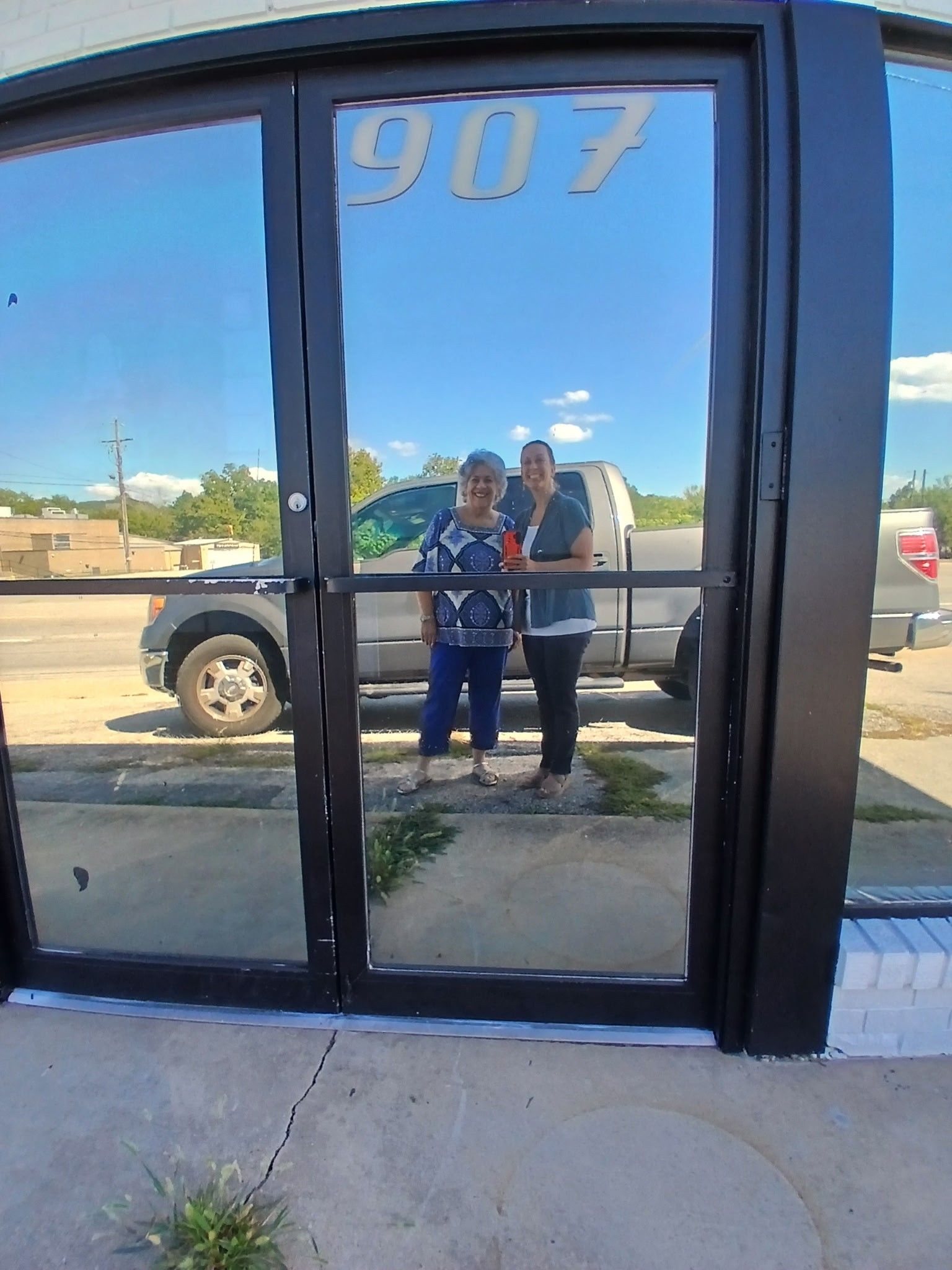 Two people reflected in the glass doors of a building, a truck and the number 