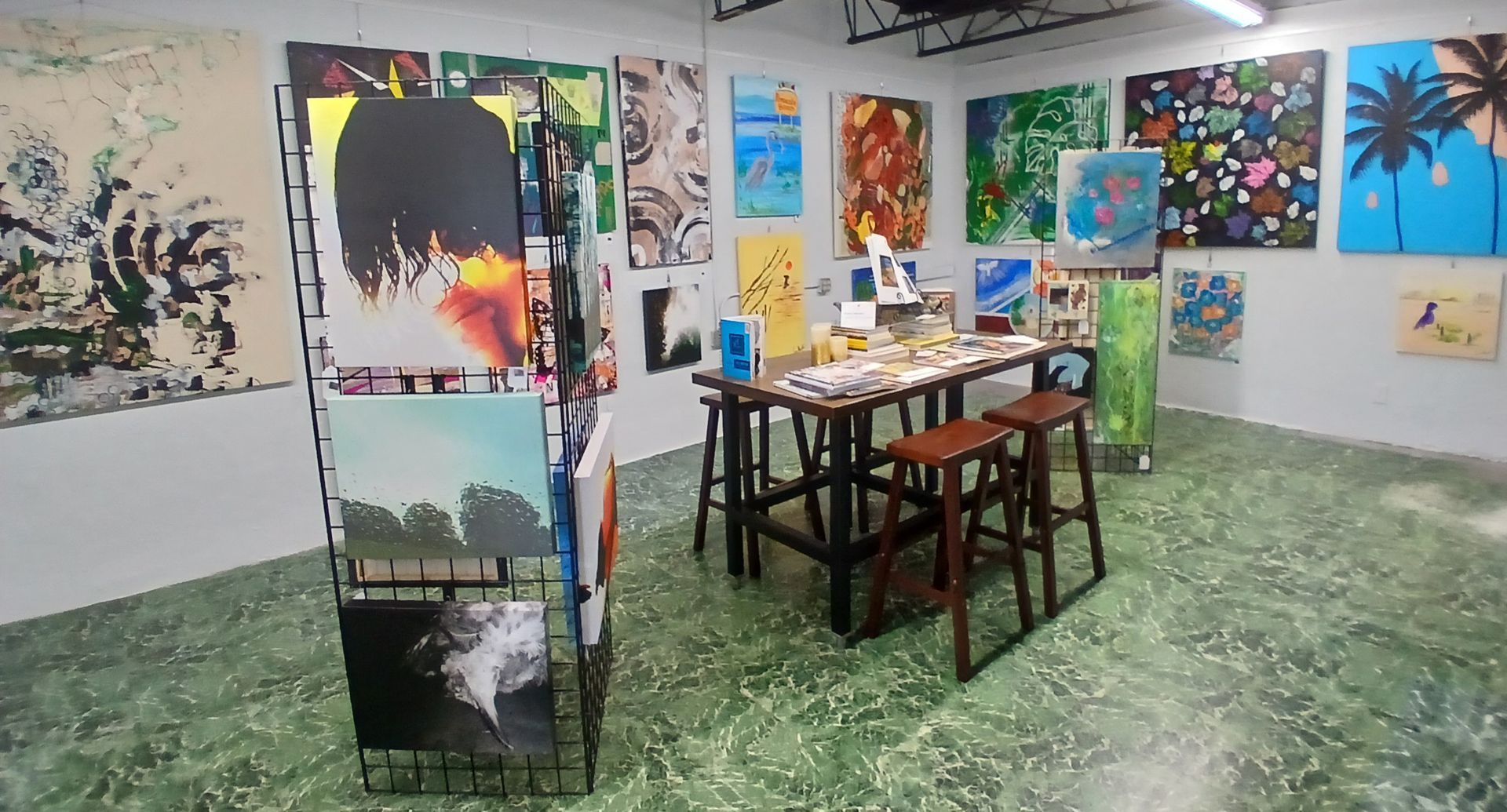 Display of many small, colorful abstract art prints hanging on a slatted wall.