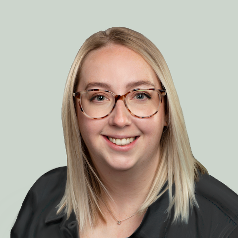 Headshot of Nina McCartney, a blonde white woman with tortoiseshell glasses. She wears a black shirt and mint background