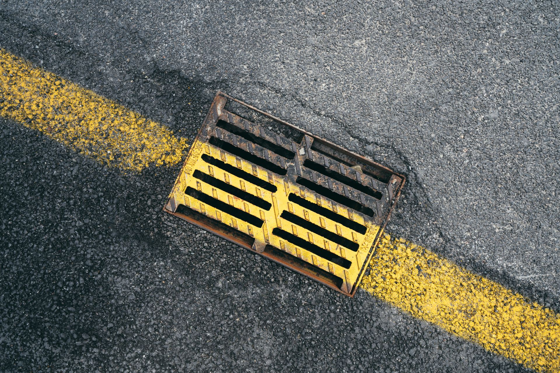 Close-up of a house corner with black roof, gutters, and dark fascia against a light blue sky.