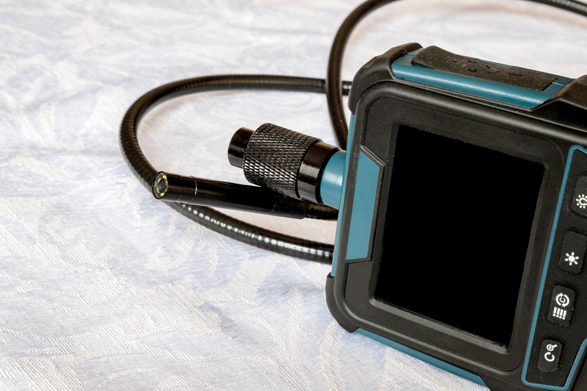 Borescope inspection camera with a black and teal display and flexible cable. Black screen.