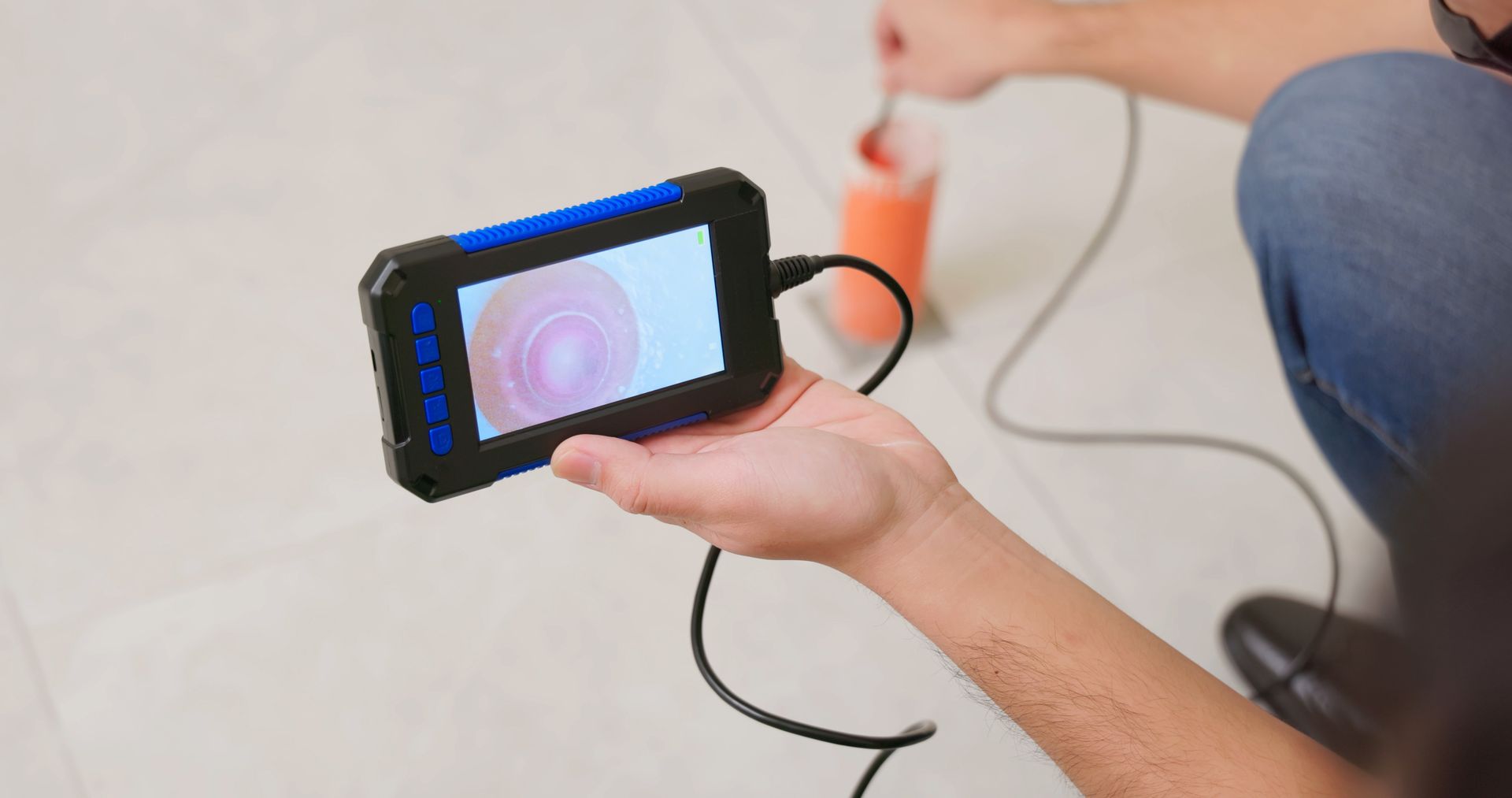 Person holding a digital inspection camera, displaying a close-up image of a surface. Person holding a digital inspection camera, displaying a close-up image of a surface.
