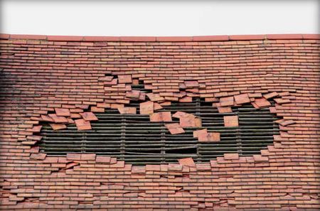 Wall with a large hole, revealing a dark interior. Red bricks are broken and scattered around the hole.