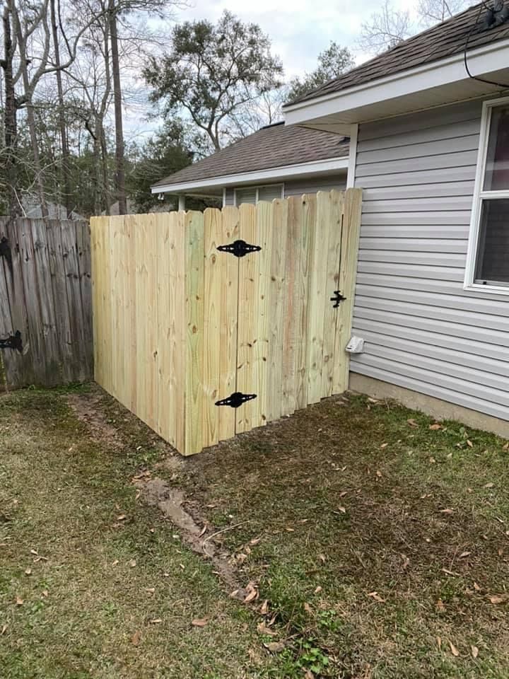 Wooden privacy fence attached to a house, separating a yard area.