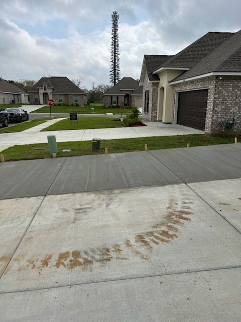 A new home with a circular dirt tire track on the driveway, cell tower in the background.