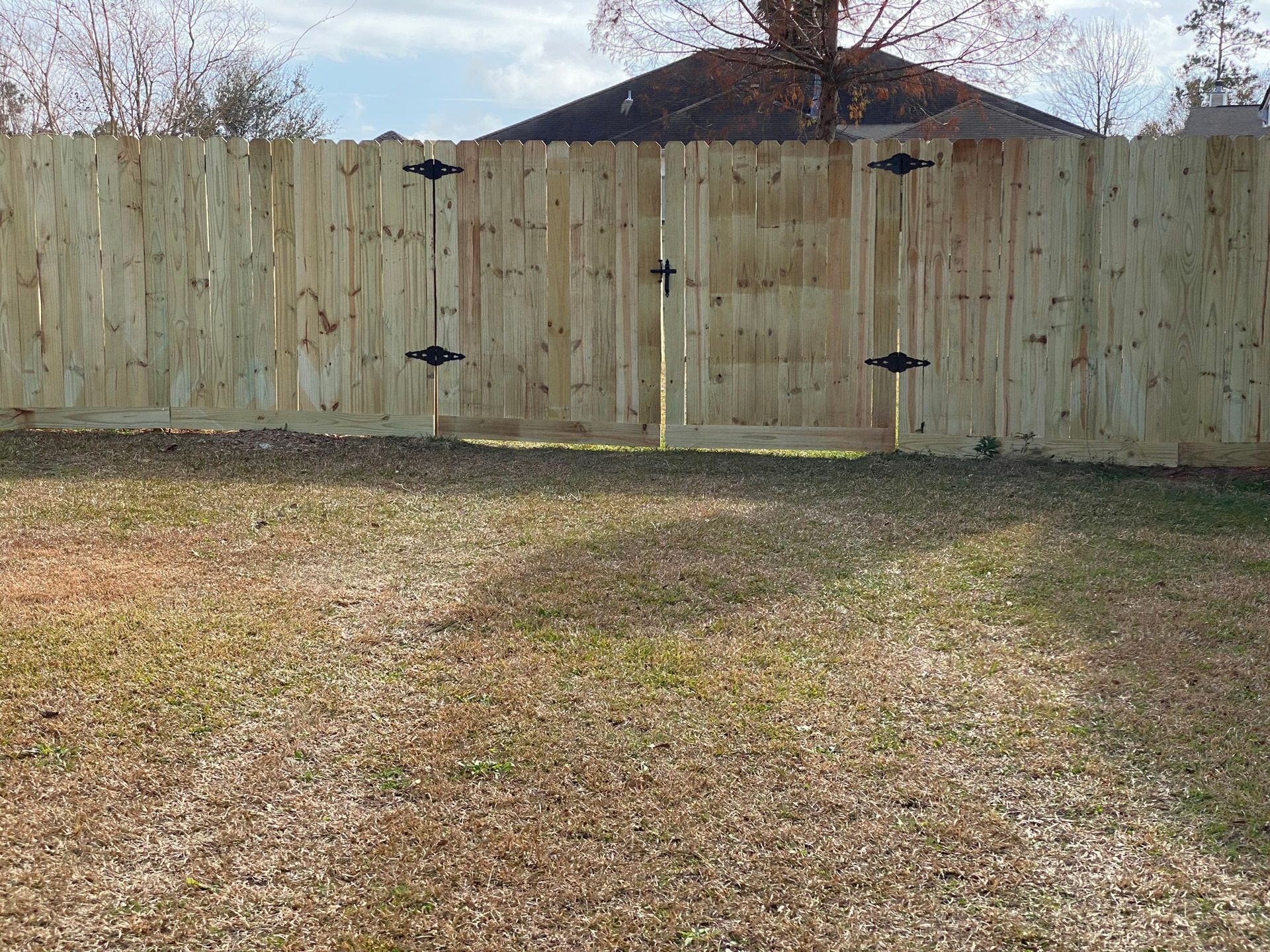 Wooden fence with gate in a grassy yard.