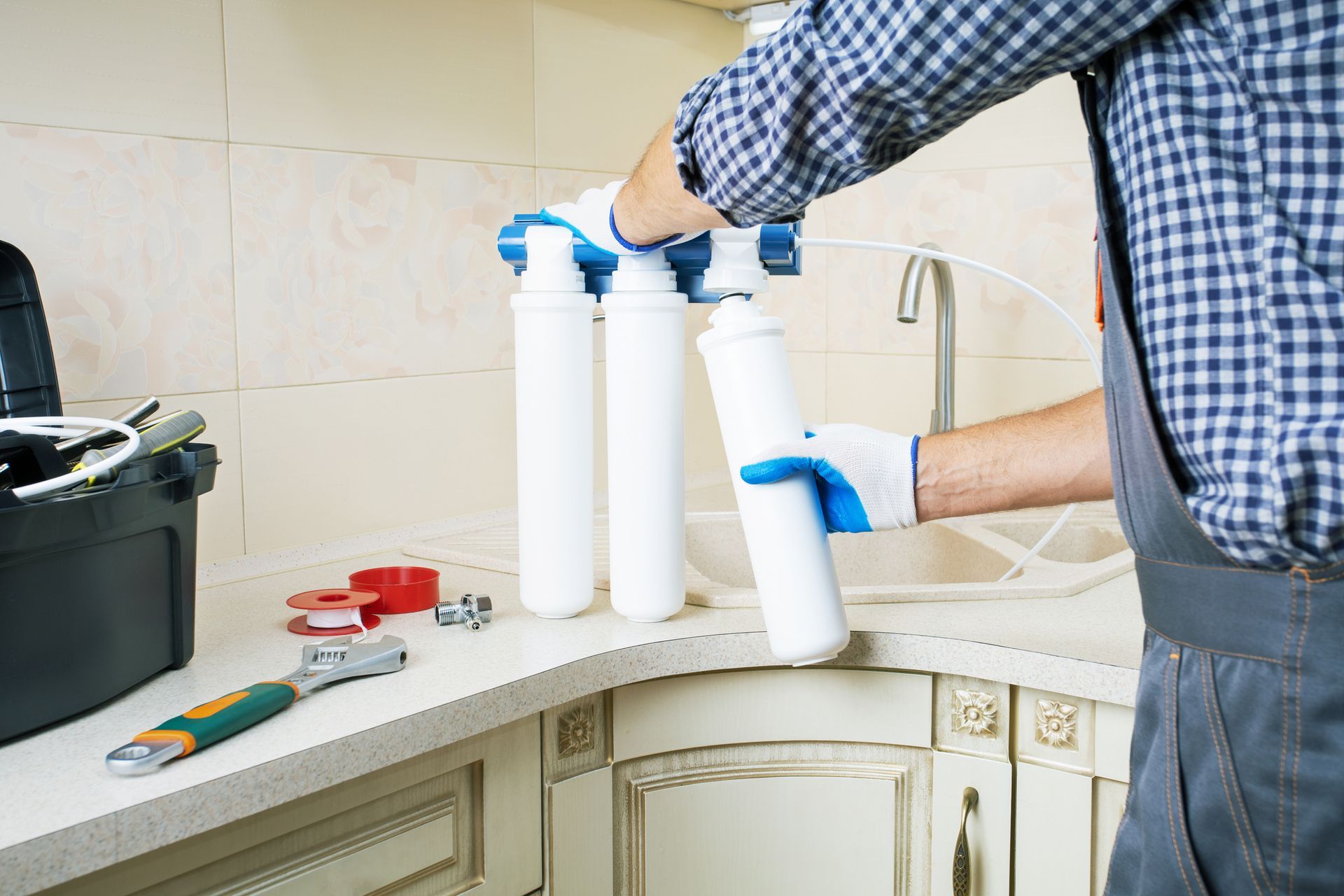 A man is installing a water filter in a kitchen.
