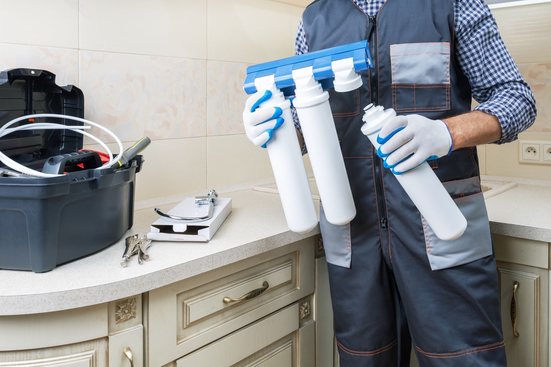 A man is holding a water filter in his hands in a kitchen.