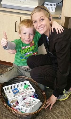 A woman is kneeling next to a young boy who is giving a thumbs up.