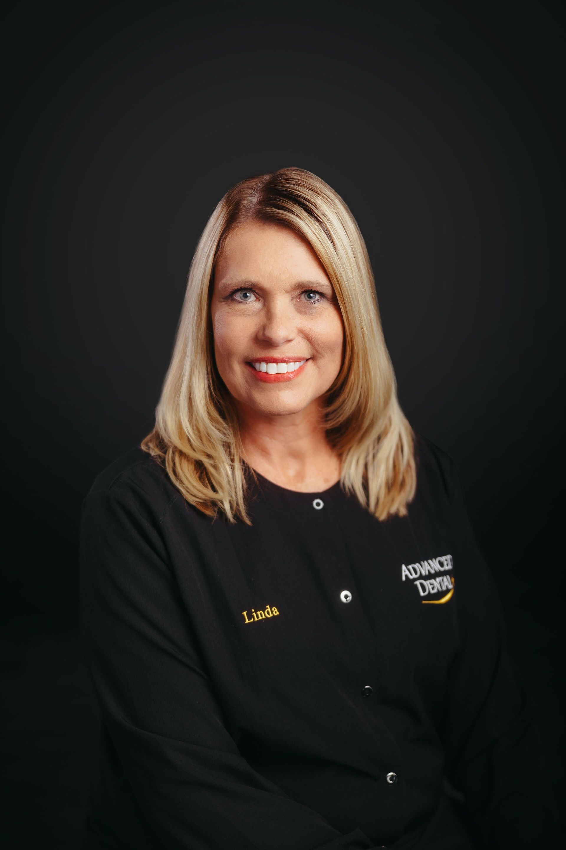 A woman is wearing a black jacket and smiling for the camera.