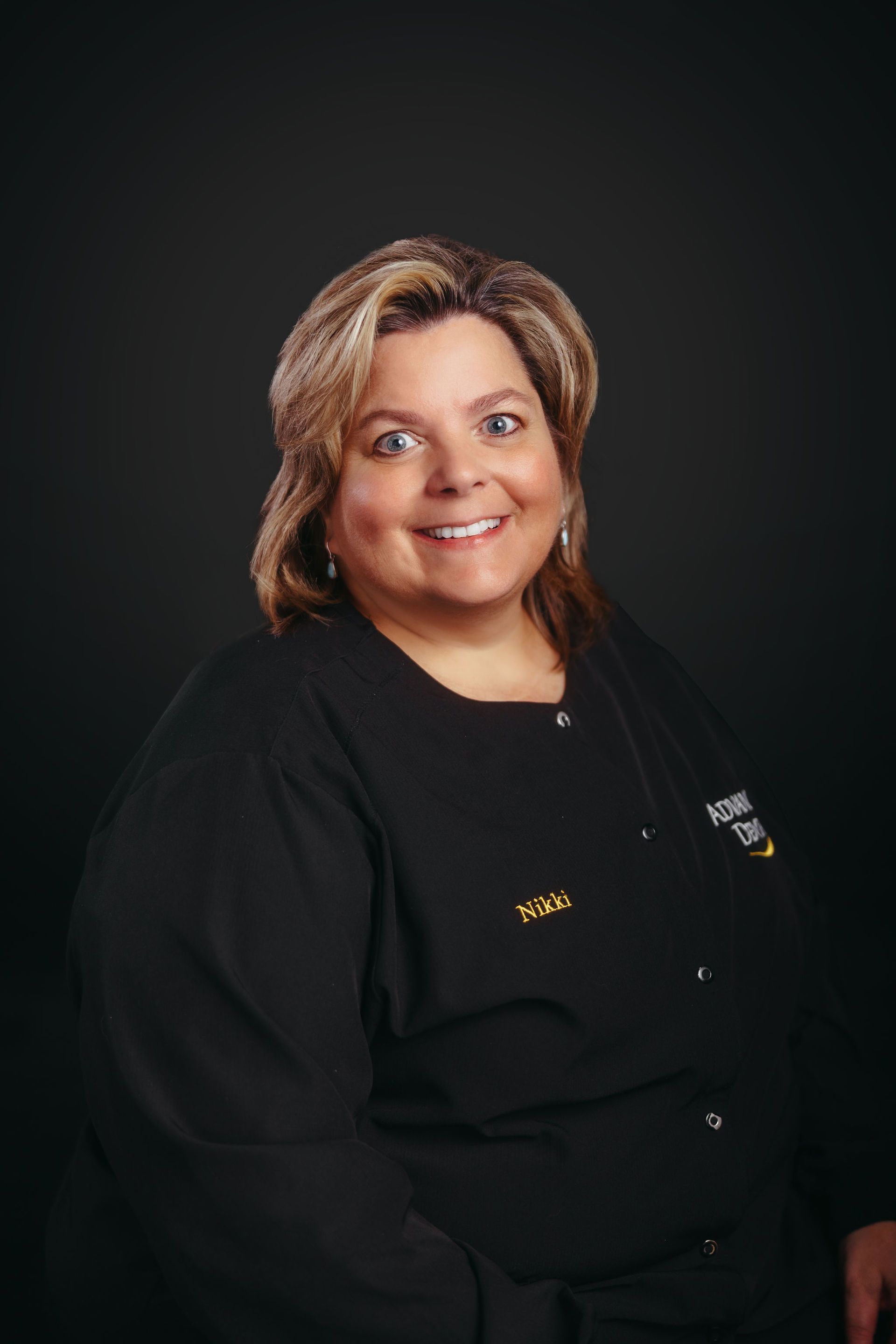 A woman in a black shirt is smiling for the camera.