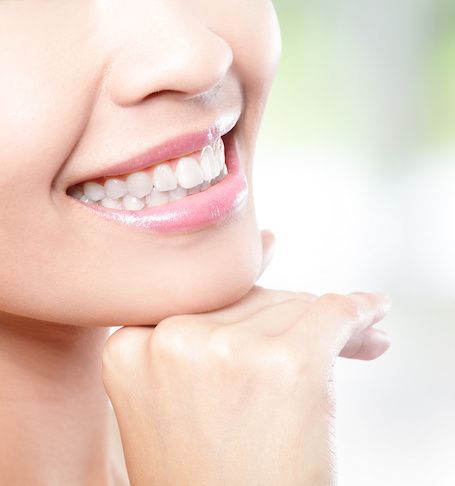 A close up of a woman 's smile with her hand on her chin.