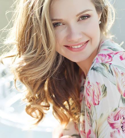 The woman is wearing a floral shirt and smiling for the camera.