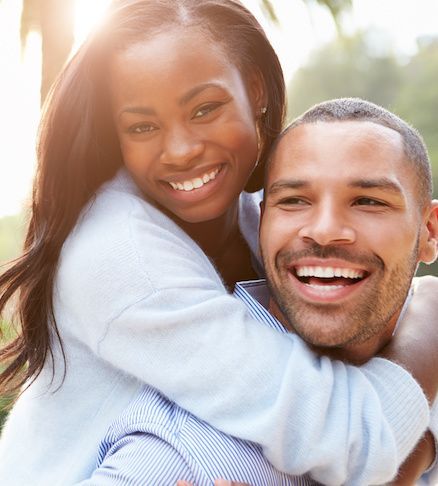 A man is carrying a woman on his back and they are smiling.