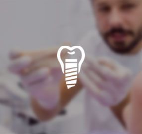 A man is holding a tooth with a screw in it.