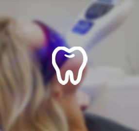 A woman is getting her teeth whitened in a dental office.