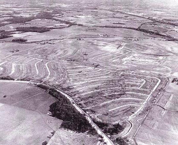 Aerial view of a snow-covered industrial landscape with roads, fields, and terraced earthworks