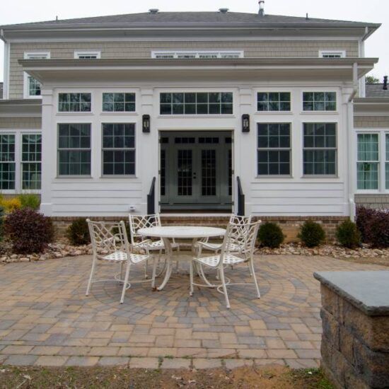 White house patio with white metal table and chairs on a stone paver patio