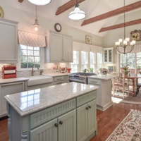 Bright airy kitchen with white cabinets, mint island, marble counters, wood floors, and pendant lights