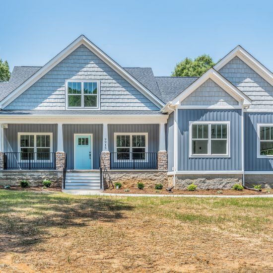 Blue-gray house with white trim, turquoise front door, and front porch on a sunny day